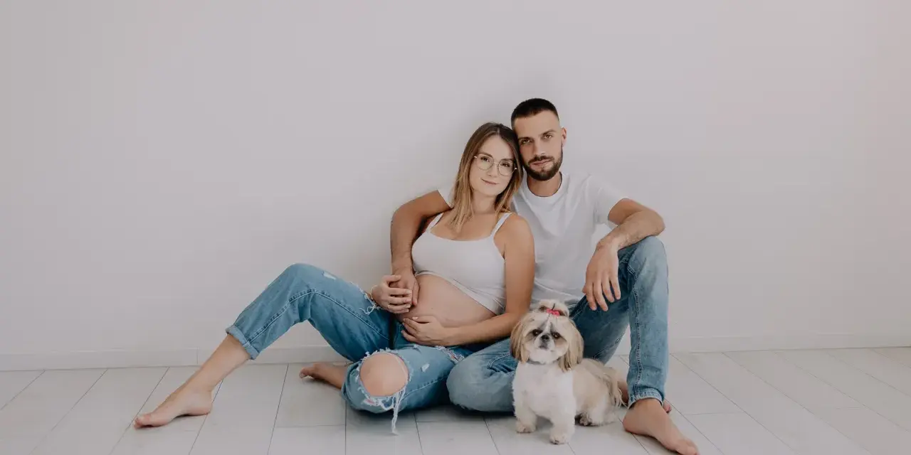 Ciąża w obiektywie laura kania fotografia: przyszli rodzice z pieskiem siedzą na podłodze.
