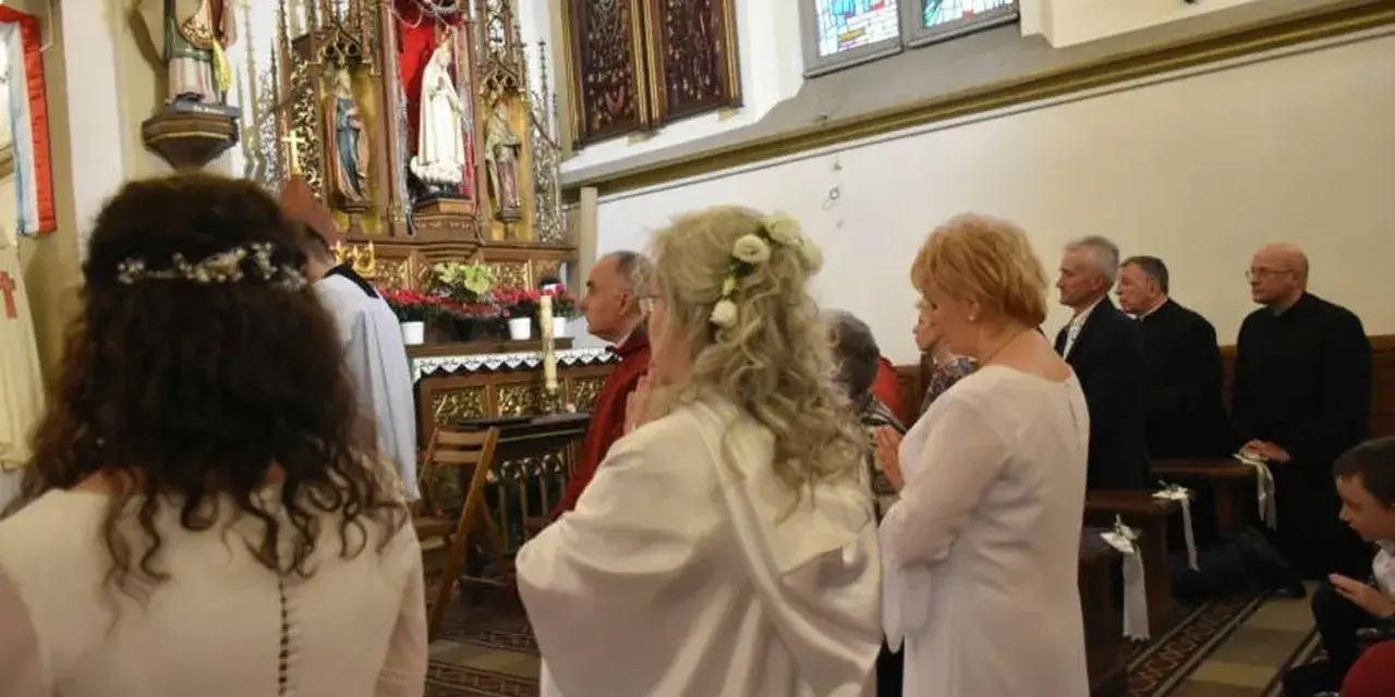Uroczystość w kościele. Kobieta w białej sukni, z kwiatami we włosach, klęczy. To moment konsekracji, ważny dla dziewicy konsekrowanej.