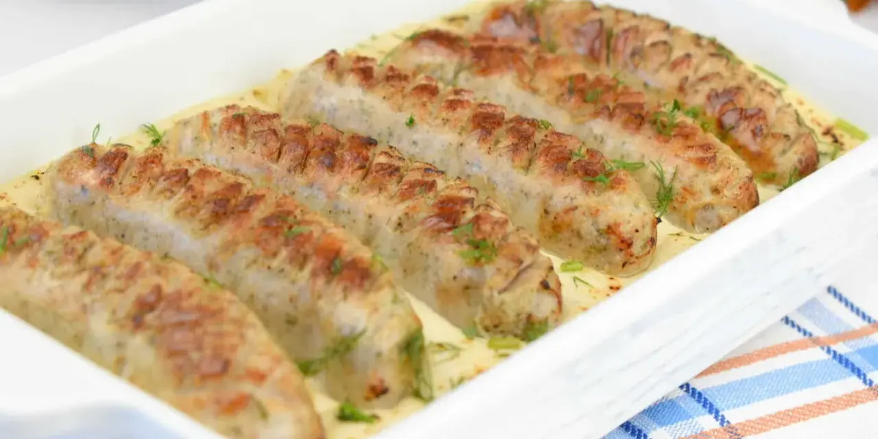 Aromaticzna biała kiełbasa w sosie chrzanowo-musztardowym, udekorowana świeżym koperkiem, podana w białej zapiekance.