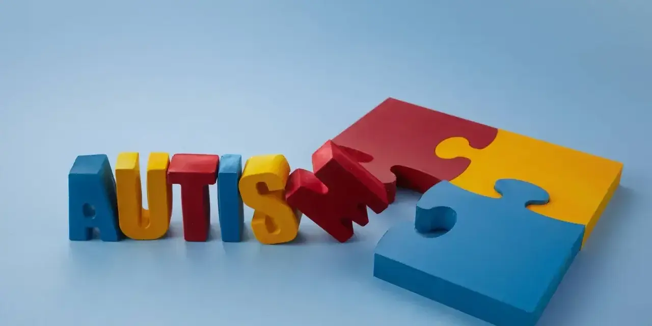 Kolorowe litery układają się w napis "AUTISM", obok fragmenty puzzli. Szukamy leków na autyzm dla dzieci, by pomóc im w rozwoju.