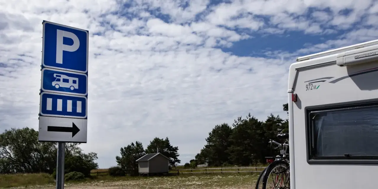 Parkeringsskylt för husbil och personbil klass 2 visar vägen till en campingplats. En husbil står parkerad.