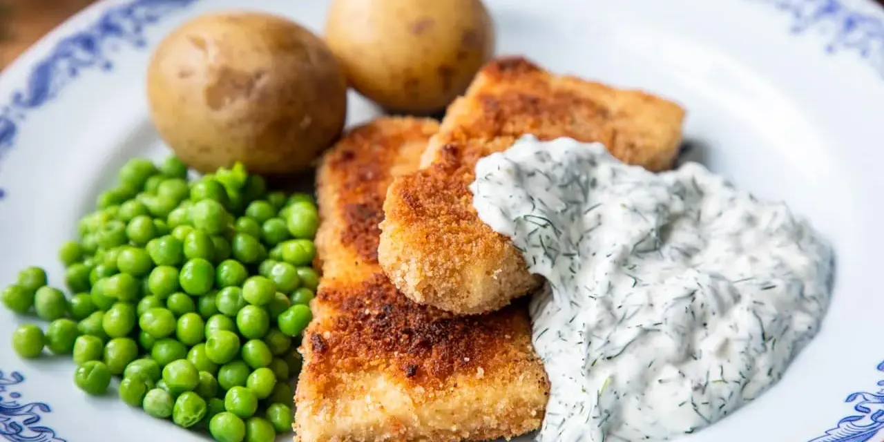 Panerad fisk med kokt potatis, gröna ärtor och en krämig skolans dillsås.