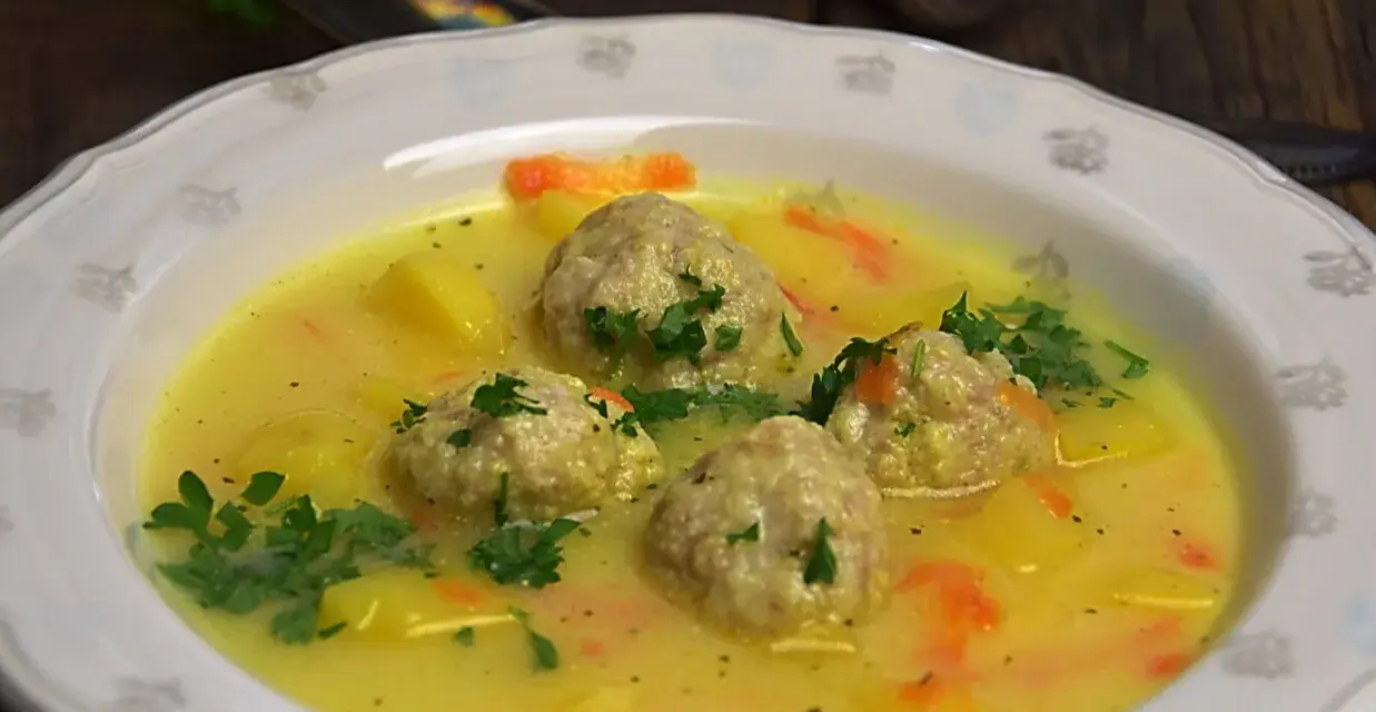 Aksamitna zupa klopsowa babci z ziemniakami i marchewką, udekorowana natką pietruszki. Pyszne wspomnienie dzieciństwa.