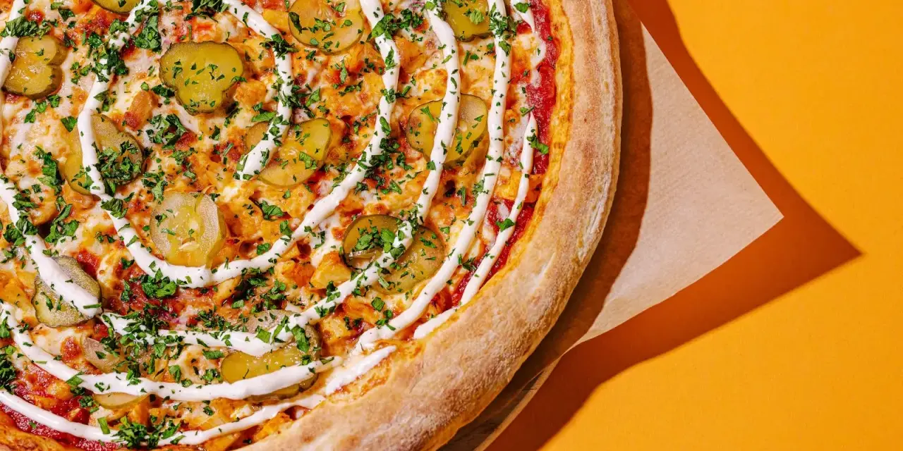 Apetyczna pizza z ogórkiem i sosem, idealna na szybki posiłek. Zastanawiasz się, ile kosztuje pizza we Włoszech?