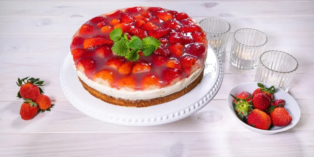 Eine köstliche Erdbeer Joghurt Sahne Torte, bedeckt mit frischen Erdbeeren und Tortenguss, garniert mit Minze.