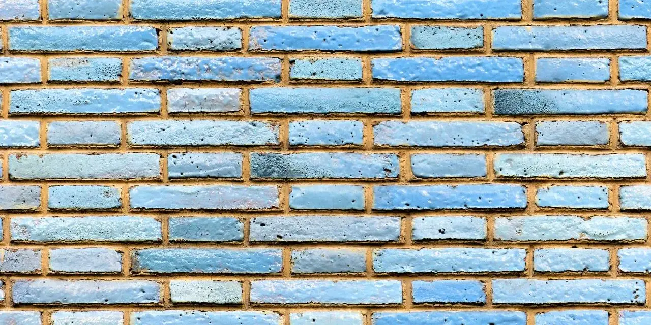 Textura de ladrillo visto pintado de azul claro, con juntas de mortero amarillentas.