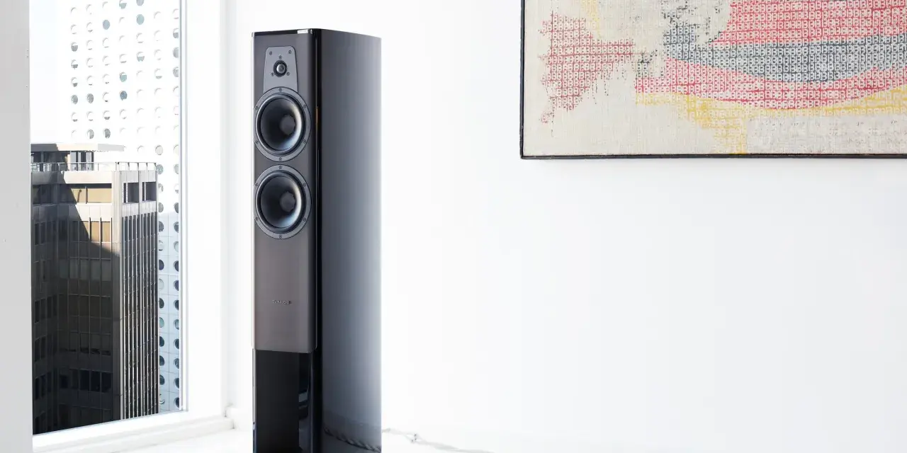 Elegancki głośnik Dynaudio Contour 30 w nowoczesnym wnętrzu, obok okna z widokiem na miasto.