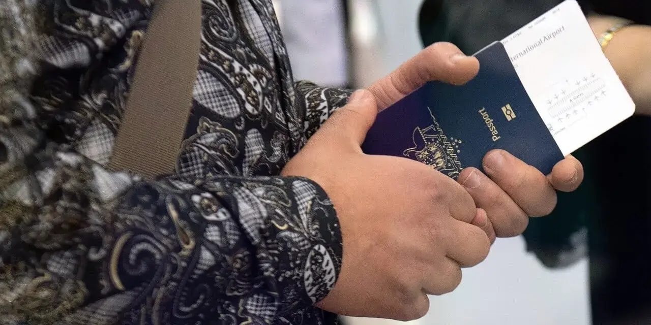 Dłoń trzyma paszport i bilet lotniczy. Czy przy zakupie biletu lotniczego potrzebny jest paszport? Tak, do podróży zagranicznych.