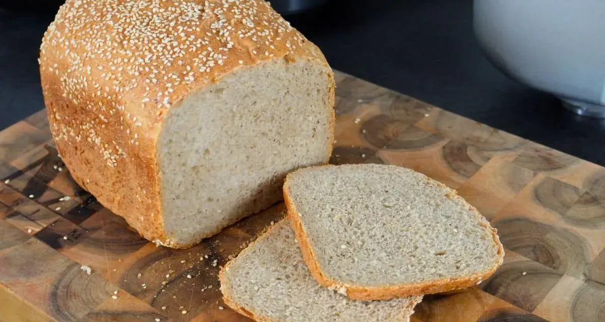 Frisch gebackenes sesam brot, mit zwei Scheiben auf einem Holzbrett.
