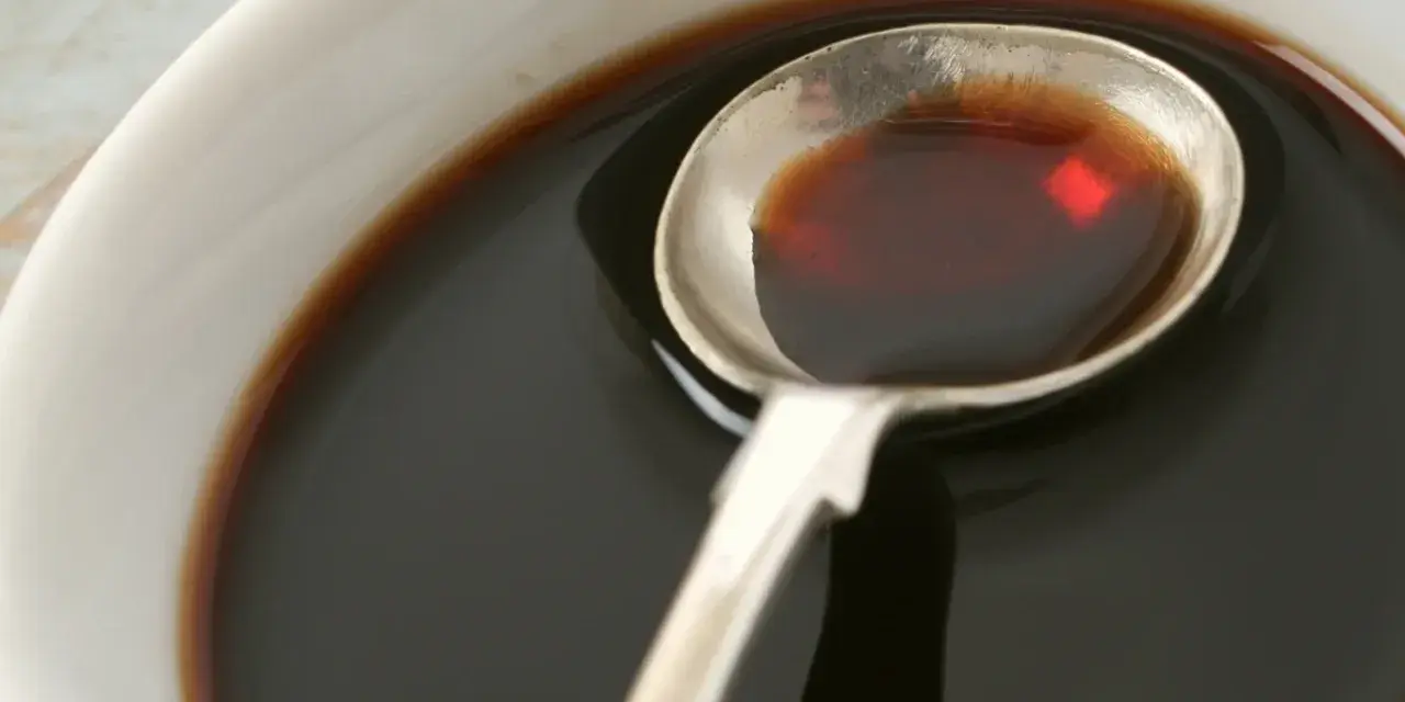 Łyżka z ciemnym płynem, idealnym do sosów i dressingów. Inspiracja do ocet balsamiczny przepisy.