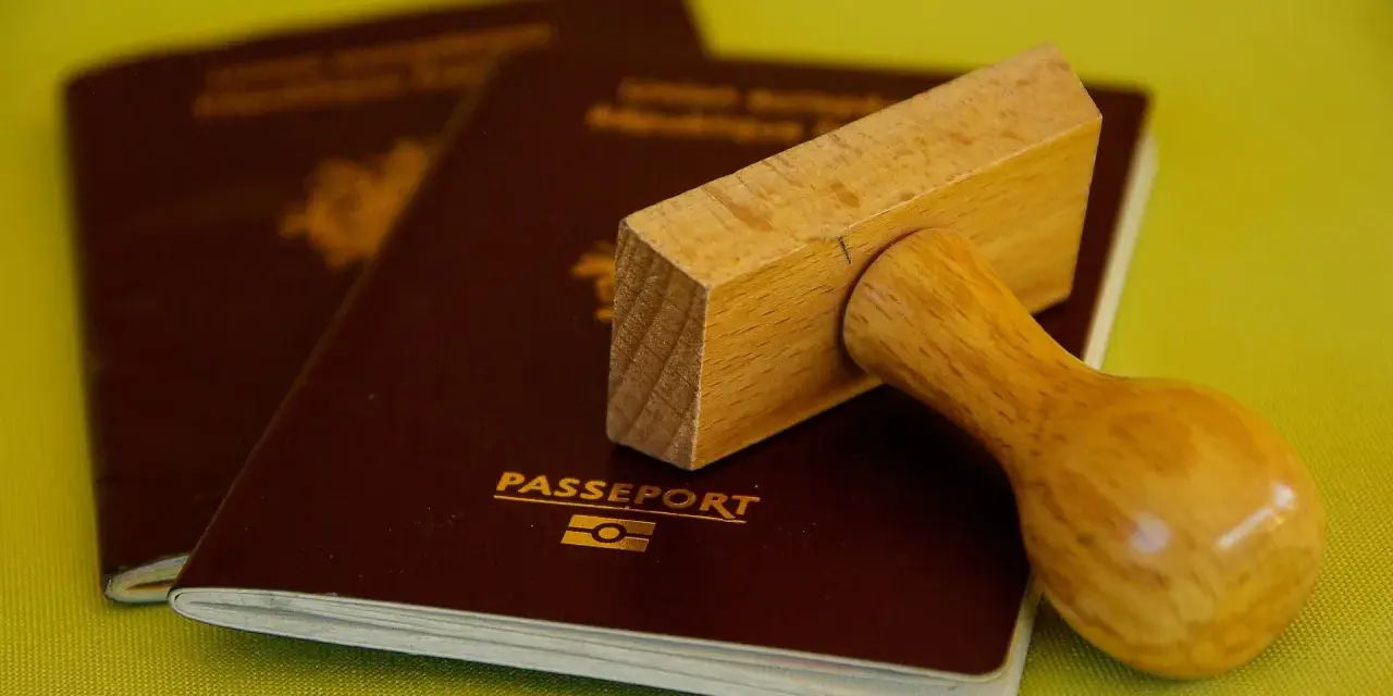 Drewniany stempel nad paszportem, gotowy do pieczętowania. Marzysz o podróży? Biuro paszportowe Lublin pomoże Ci spełnić marzenia.