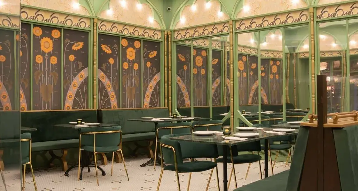 Elegante restaurante con mesas y sillas verdes, paredes decoradas con girasoles y detalles dorados. Un lugar perfecto para disfrutar de **frases restaurante** inspiradoras.
