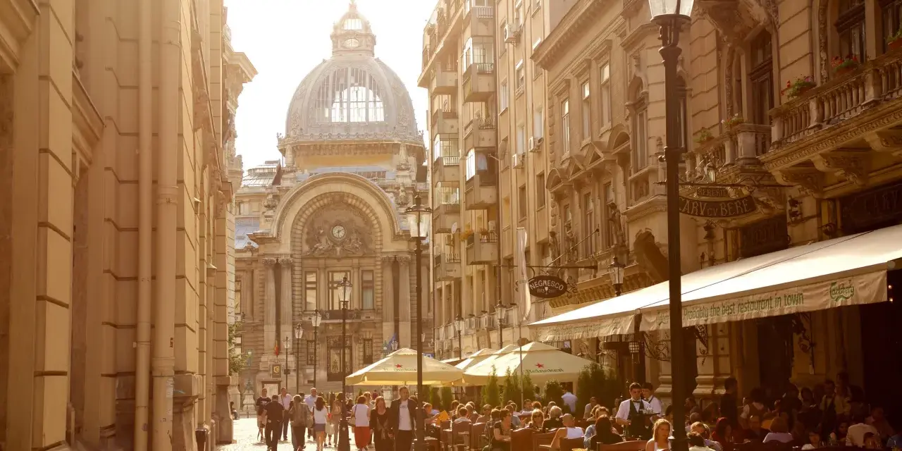 Spacerem po Bukareszcie, gdzie widać ludzi siedzących w ogródku restauracji. Czy bukareszt jest bezpieczny? Tak, wygląda na spokojne miejsce.