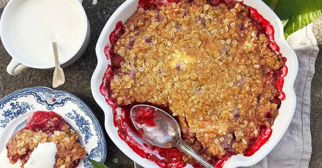 En härlig hallonpaj smulpaj med krispig topping, serverad med vaniljsås. Perfekt sommarfika!
