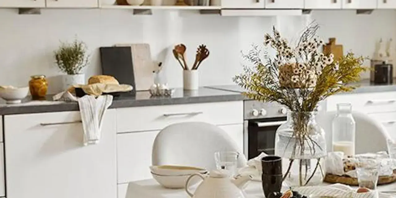 Cuisine lumineuse dans une maison style cottage anglais, avec vaisselle et bouquet de fleurs séchées sur la table.