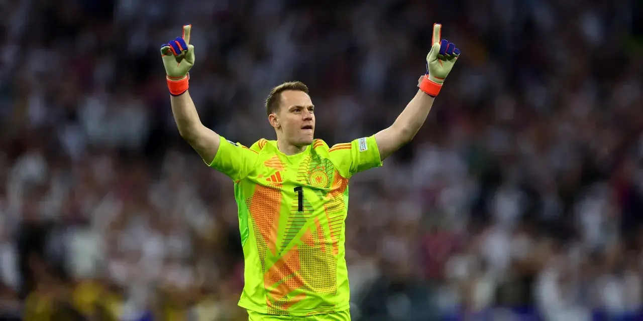 Manuel Neuer, bramkarz w neonowożółtej koszulce z numerem 1, świętuje zwycięstwo, unosząc ręce w geście triumfu.