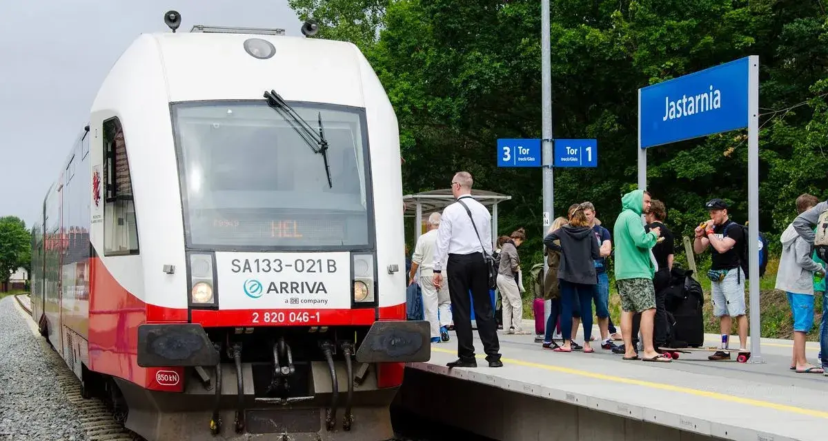 Pociąg Arriva z napisem HEL czeka na pasażerów w Jastarni. Ludzie z bagażami stoją na peronie, gotowi do podróży z Helu do Gdańska.