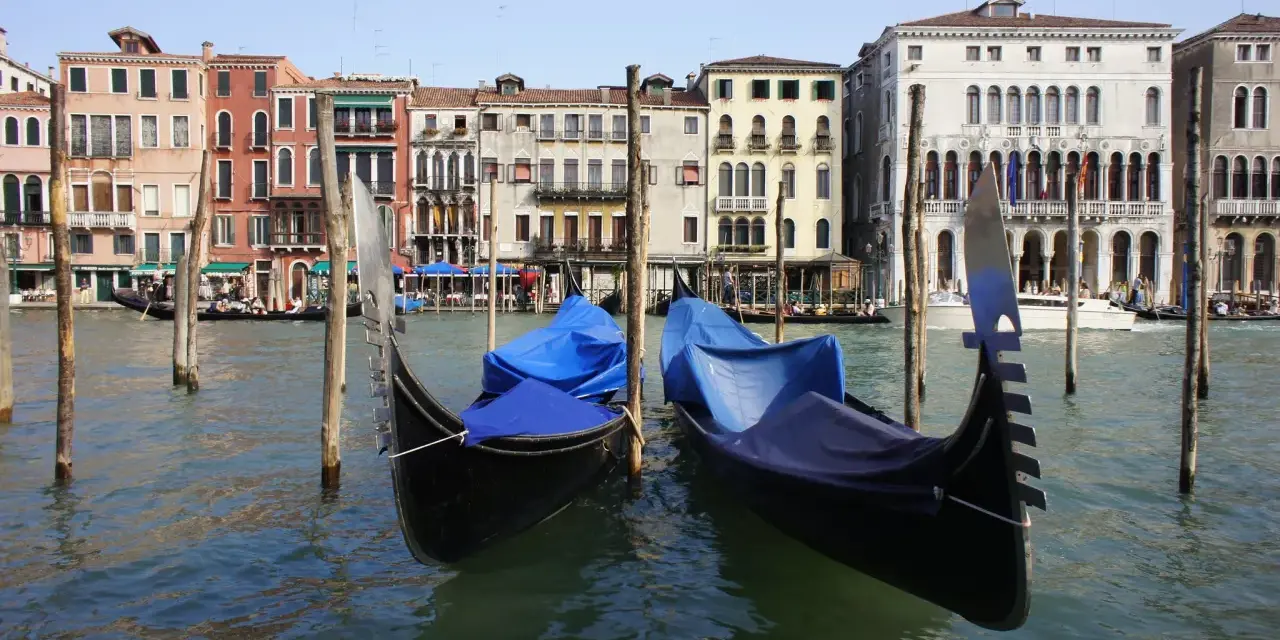 Gondole ormeggiate sul Canal Grande, pronte per le escursioni a Venezia. Edifici storici sullo sfondo.