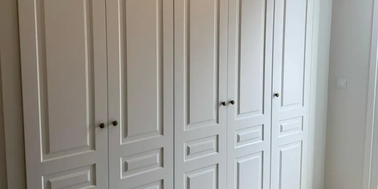 Armario empotrado blanco con puertas de paneles y tiradores oscuros. Perfecto para forrar armario empotrado y dar un toque elegante.