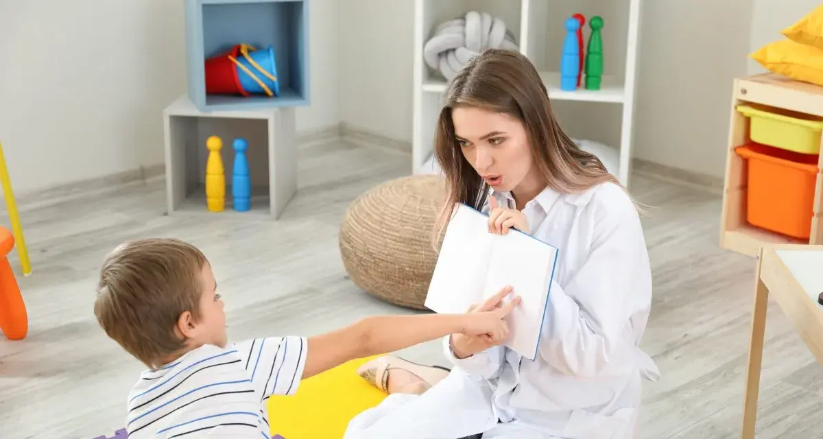 Terapeuta pracuje z dzieckiem nad mową skandowaną, używając książki jako pomocy.