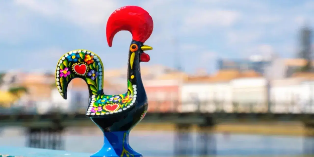 Un gallo de cerámica negro, decorado con flores y corazones, se alza orgulloso con su cresta roja.