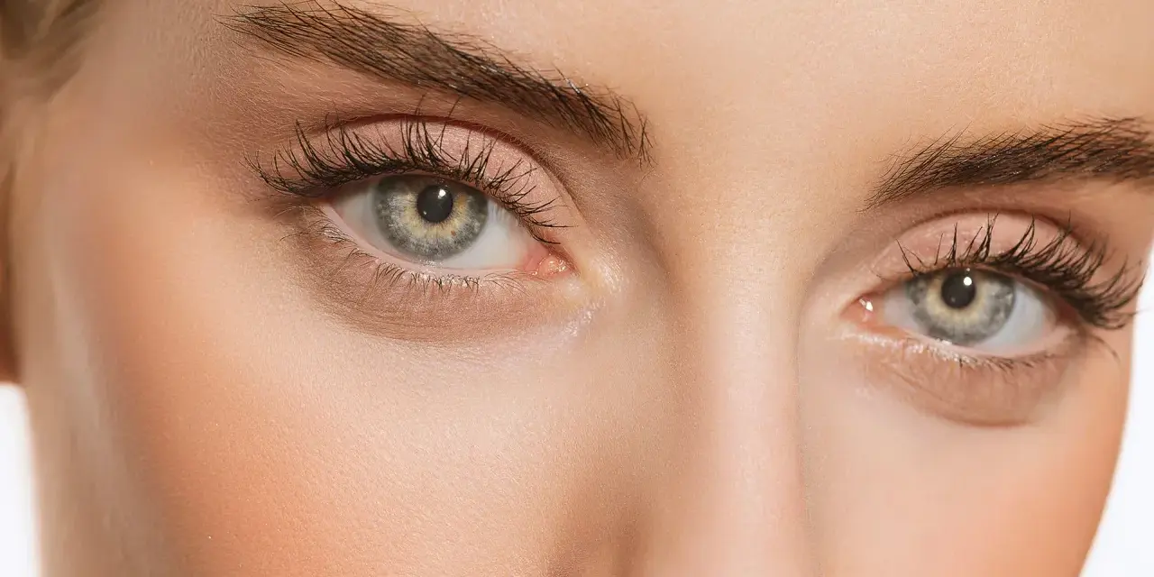 Maquillage subtil pour paupières tombantes, rehaussé par le regard intense derrière des lunettes imaginaires.