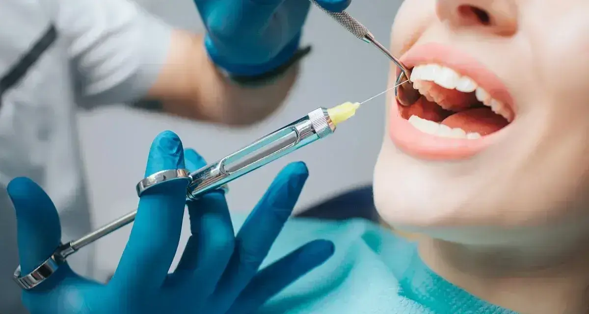 Dentysta podaje znieczulenie, przygotowując się do zabiegu, jak wyrwać mleczaka.