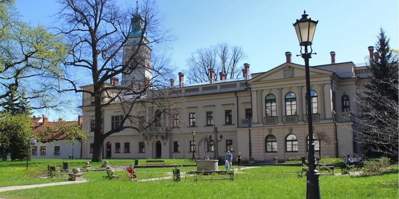 Zamek w Żywcu, z wieżą i dziedzińcem, otoczony zielenią i drzewami.