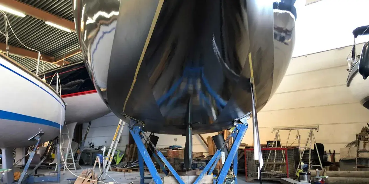 Schwarzer Rumpf einer Yacht im Trockendock, bereit, das Antifouling zu erneuern.
