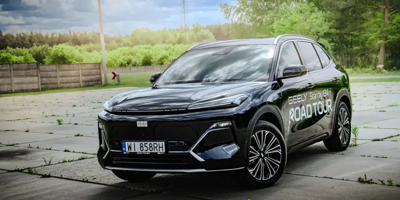 Czarny Geely Starray EM-i gotowy na Road Tour, lśniąc na tle zieleni i chmur.