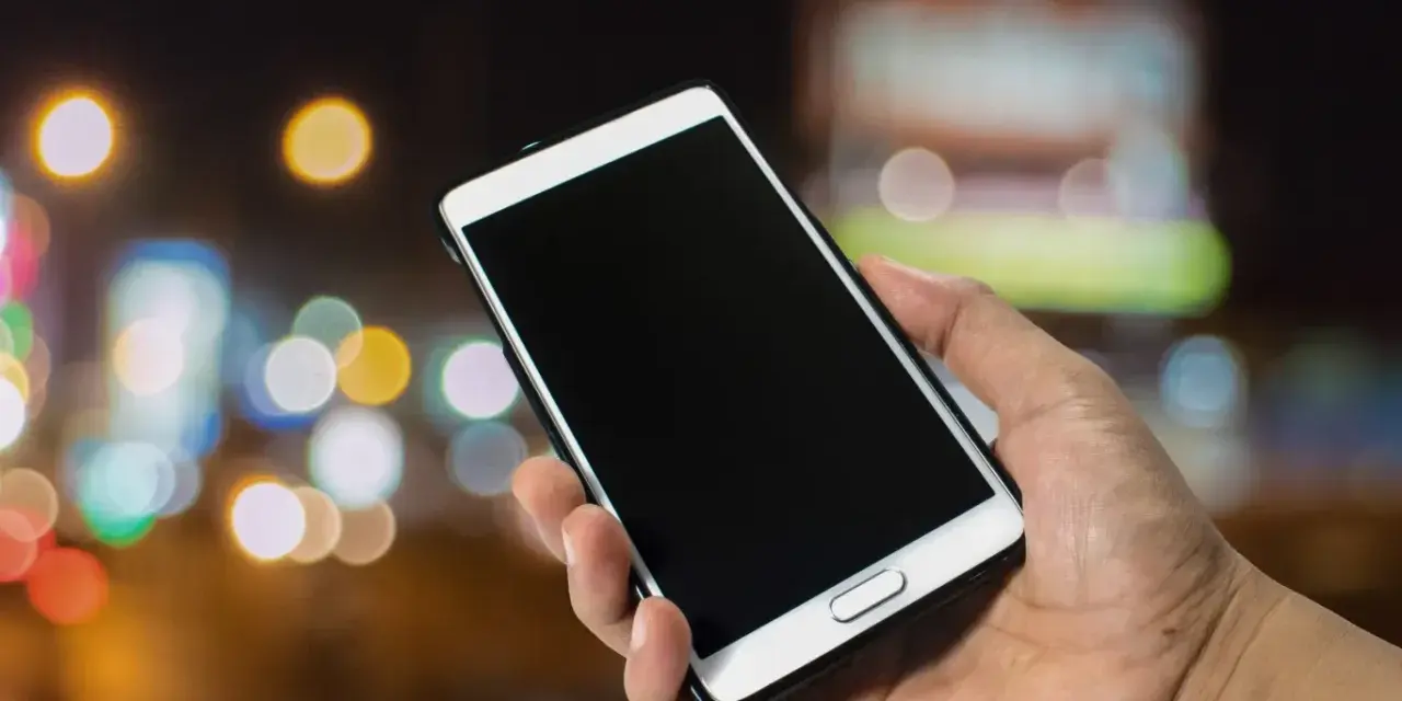 Dłoń trzyma smartfon Samsung. Zastanawiasz się, jak wyłączyć telefon Samsung bez dotyku? Oto rozwiązanie.