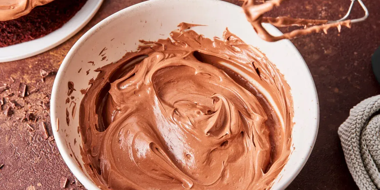 Schokocreme mit Puddingpulver, cremig und glatt, bereit für einen köstlichen Kuchen. Ein Handmixer mit Schokoladenresten liegt daneben.