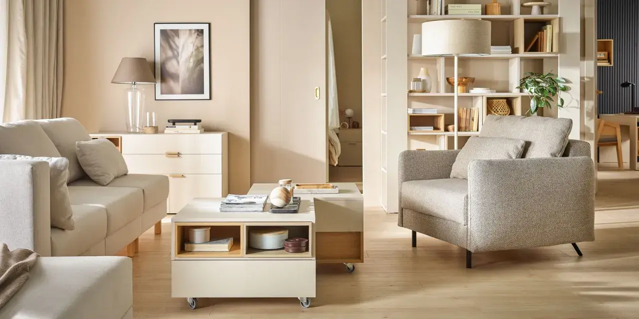 Nowoczesny salon po przemeblowaniu pokoju. Jasne meble, sofa, fotel, stolik kawowy i regał tworzą przytulną przestrzeń.
