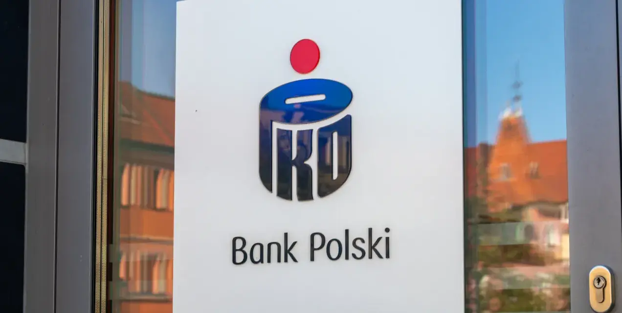 Logo PKO Bank Polski na drzwiach. W tle odbicie kamienicy.