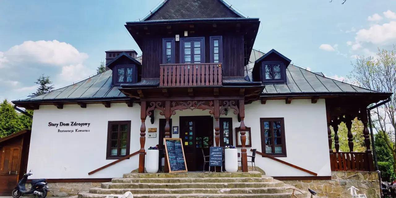 Stary Dom Zdrojowy w Beskidach, z charakterystyczną architekturą i kamiennymi schodami, zaprasza do restauracji.