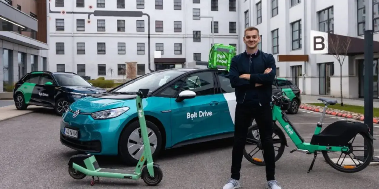 Ein Mann steht stolz neben einem Bolt Drive Auto, E-Scooter und Fahrrad. Er ist ein Bolt Fahrer, der umweltfreundliche Mobilität fördert.