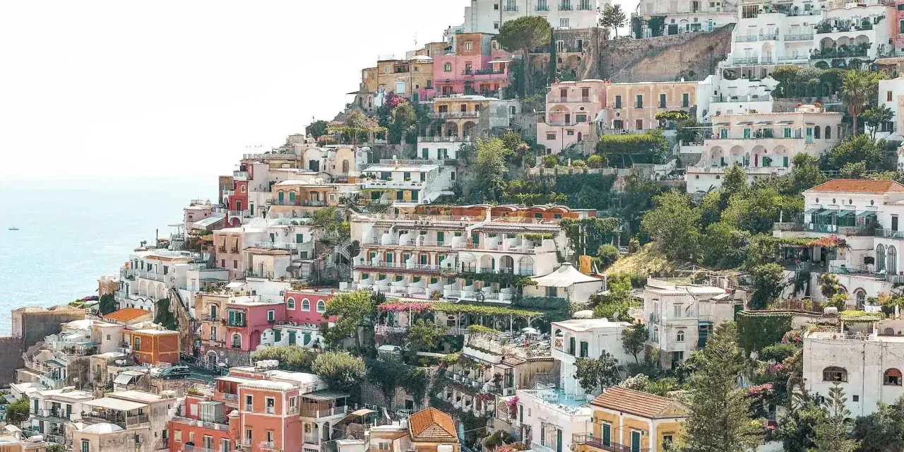 Colorful houses cascade down a hillside towards the sea, a picturesque scene perfect for any Europe itinerary.