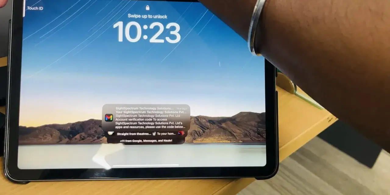 Tablet z włączonym ekranem blokady, widoczny napis "Touch ID" i godzina 10:23. Na ekranie wyświetla się powiadomienie z kodem weryfikacyjnym.
