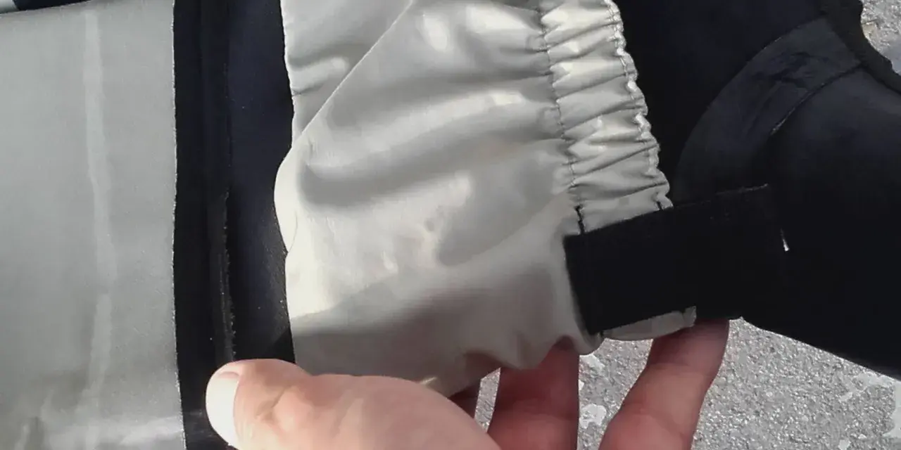 Hand hält ein Hosenbein mit elastischem Bund und Klettverschluss. Vielleicht ein Flicken für die wathose?