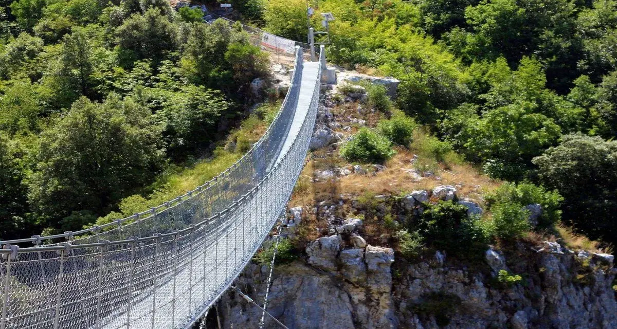 Un lungo ponte tibetano si snoda tra rocce e vegetazione lussureggiante, offrendo un'avventura mozzafiato nei dintorni di Salerno.