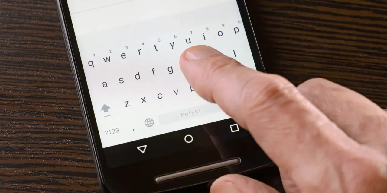Palec naciska klawisz "Polski" na klawiaturze telefonu, aby włączyć polskie znaki w SMS.
