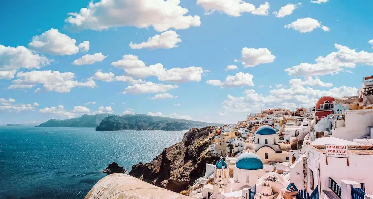 Widok na białe domy z niebieskimi kopułami na greckiej wyspie Santorini nad morzem.