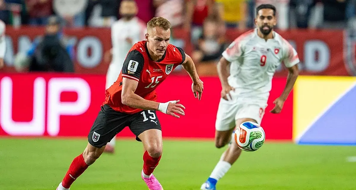 Jugadores de fútbol en acción. El número 15 de Austria corre con el balón, mientras otro jugador se acerca. ¿Quién juega hoy?