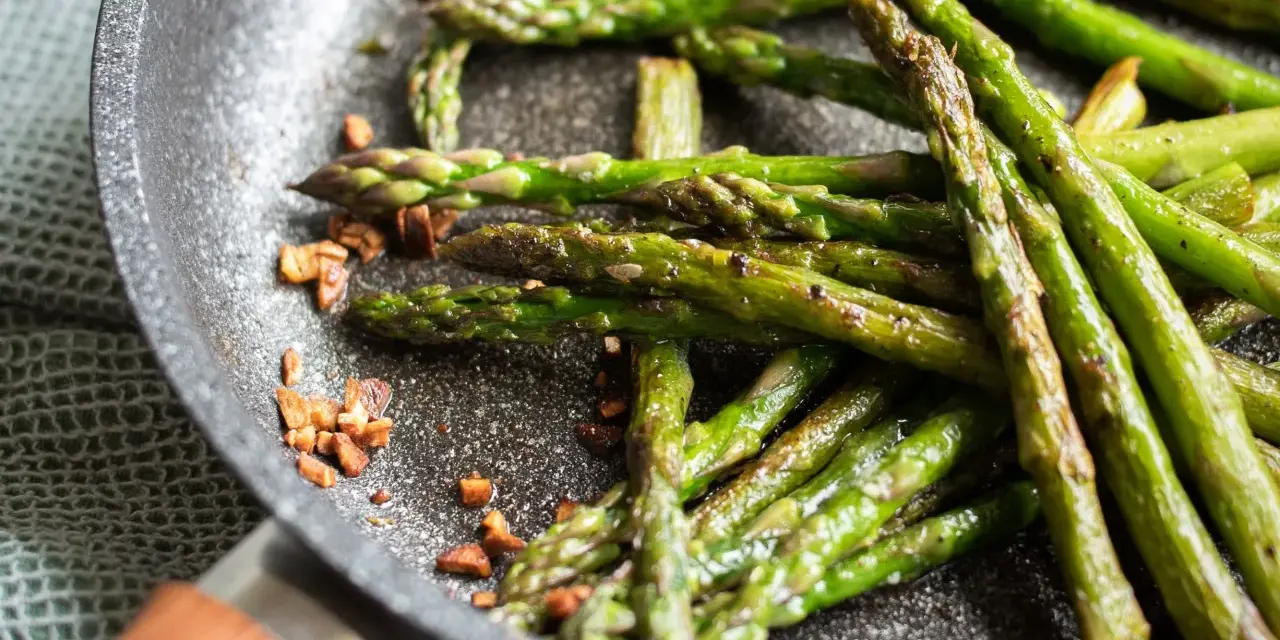 Asparagi in padella, croccanti e saporiti, con pezzetti di pancetta tostata che aggiungono un tocco in più.