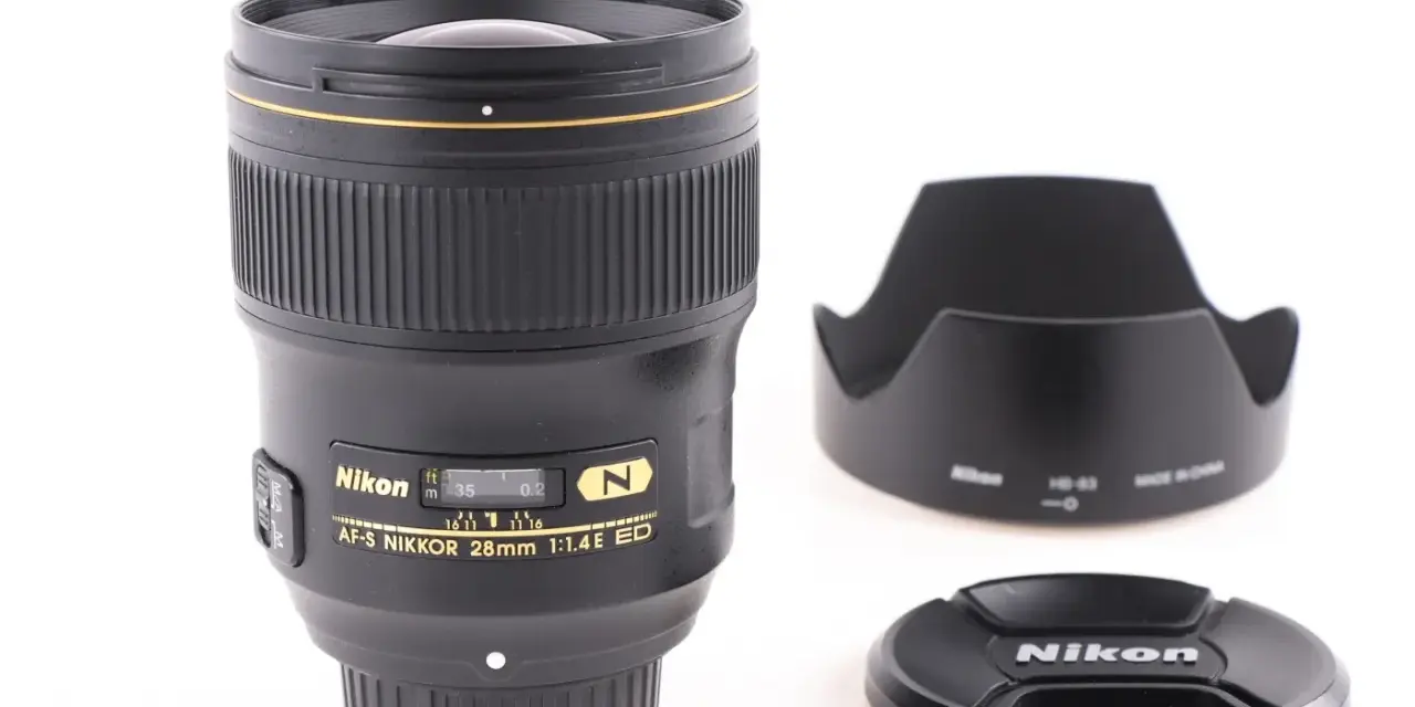 Obiektyw AF-S NIKKOR 28mm 1:1.4E ED z osłoną przeciwsłoneczną i deklem. Jasne oznaczenia obiektywów Nikon.