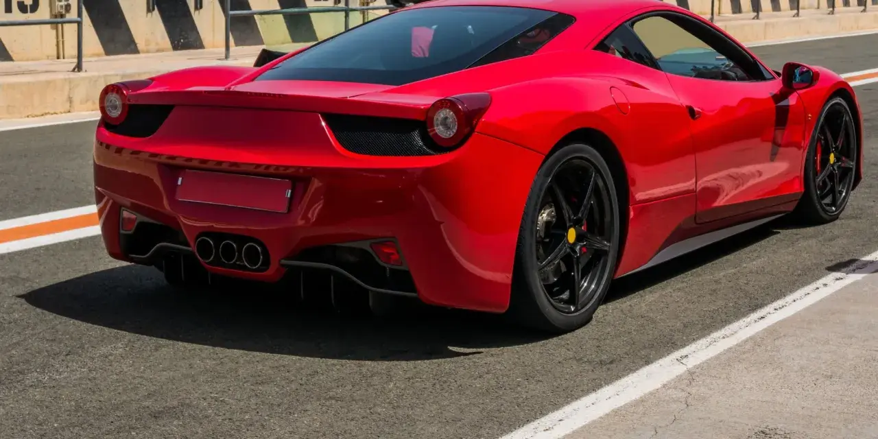 Czerwone Ferrari 458 Italia na torze wyścigowym, widok z tyłu.