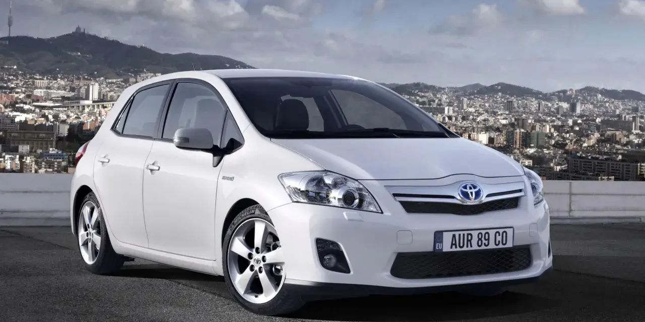 Biała Toyota Auris hybryda na tle miasta. Czy warto zainwestować w ten model?