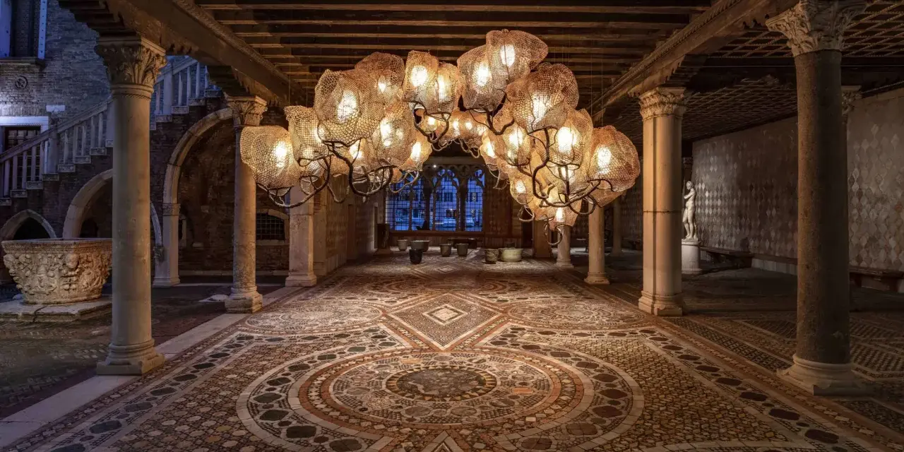 Interni Ca' d'Oro: un lampadario scenografico illumina il cortile con pavimenti a mosaico e colonne antiche.