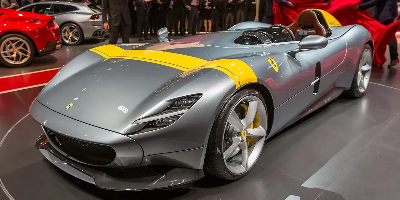 Szary Ferrari Monza SP1 z żółtymi pasami, odsłaniany na scenie.