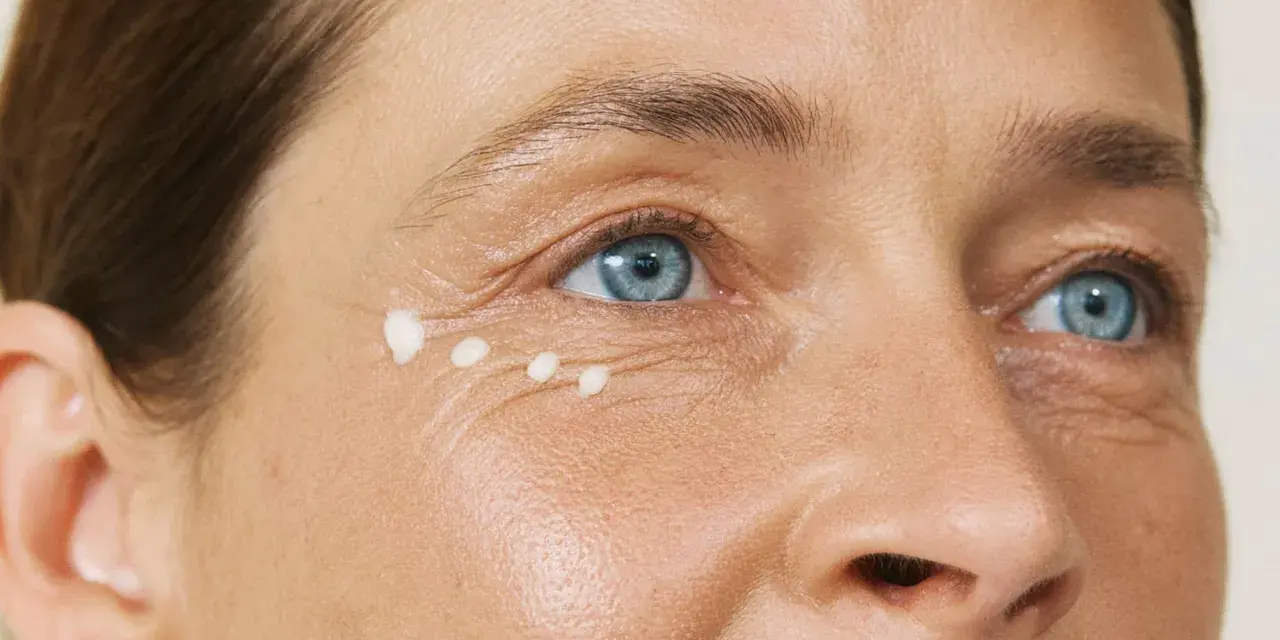 Augenpartie einer Frau über 40 mit feinen Linien und aufgetupfter Creme.